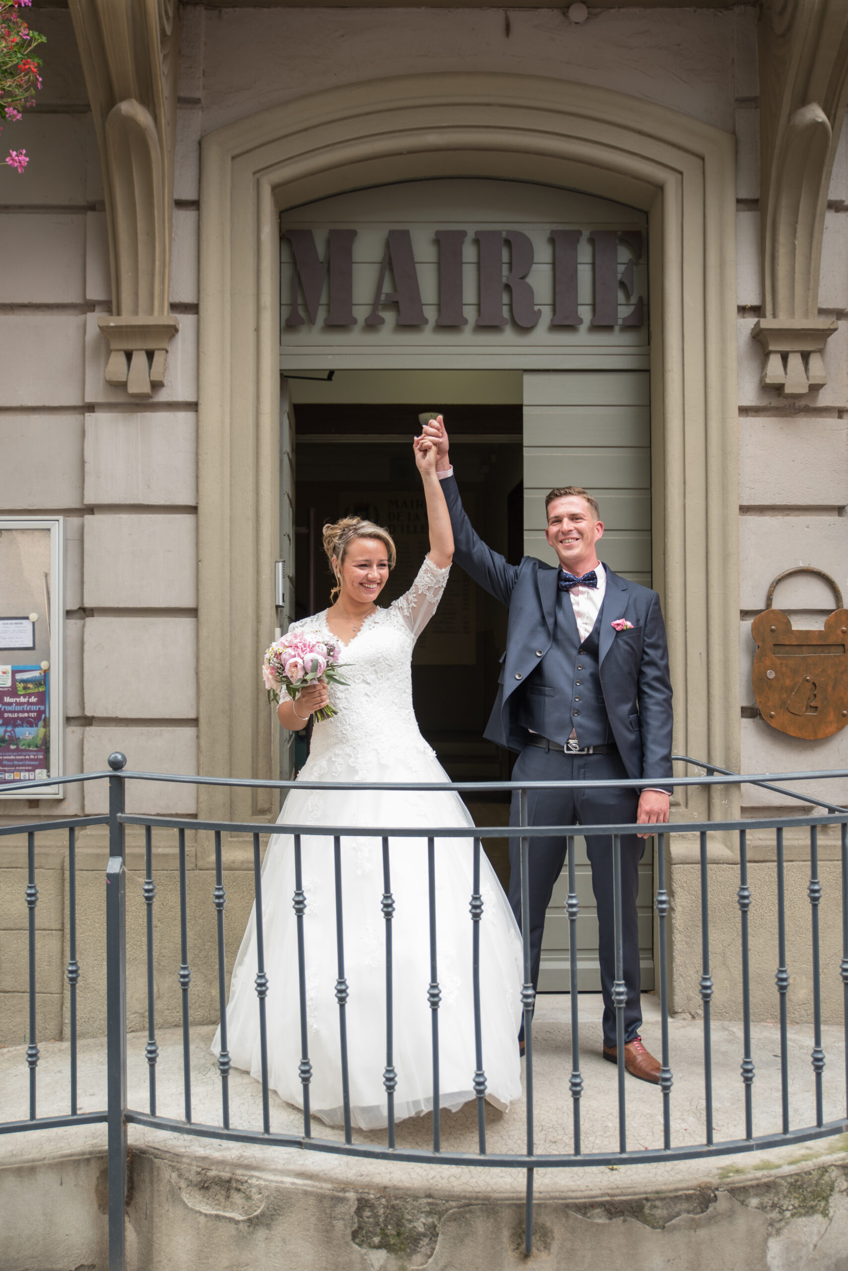Mariés levant les bras à la sortie de la mairie
