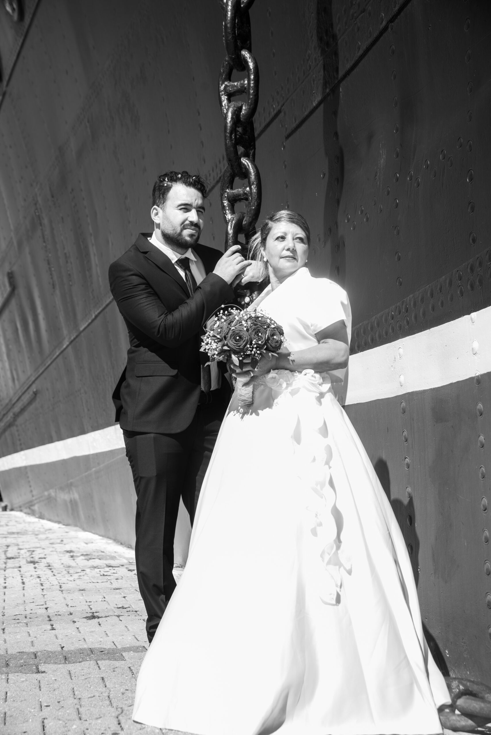Portrait vertical d’un couple de mariés contre une paroi industrielle